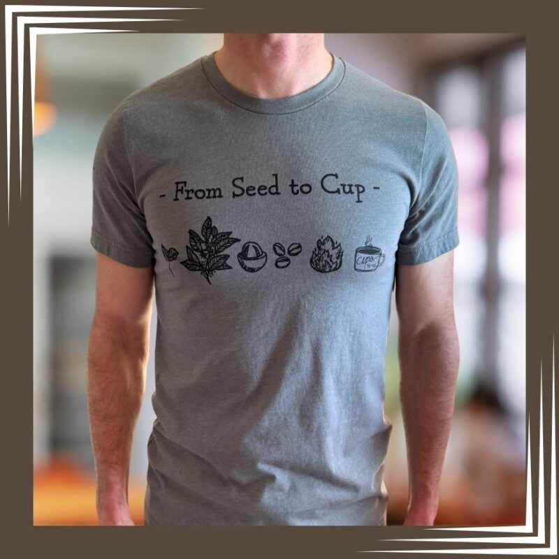 Man wearing heather gray Cups "From Seed to Cup" t-shirt with coffee process illustrations from coffee plant to final cup